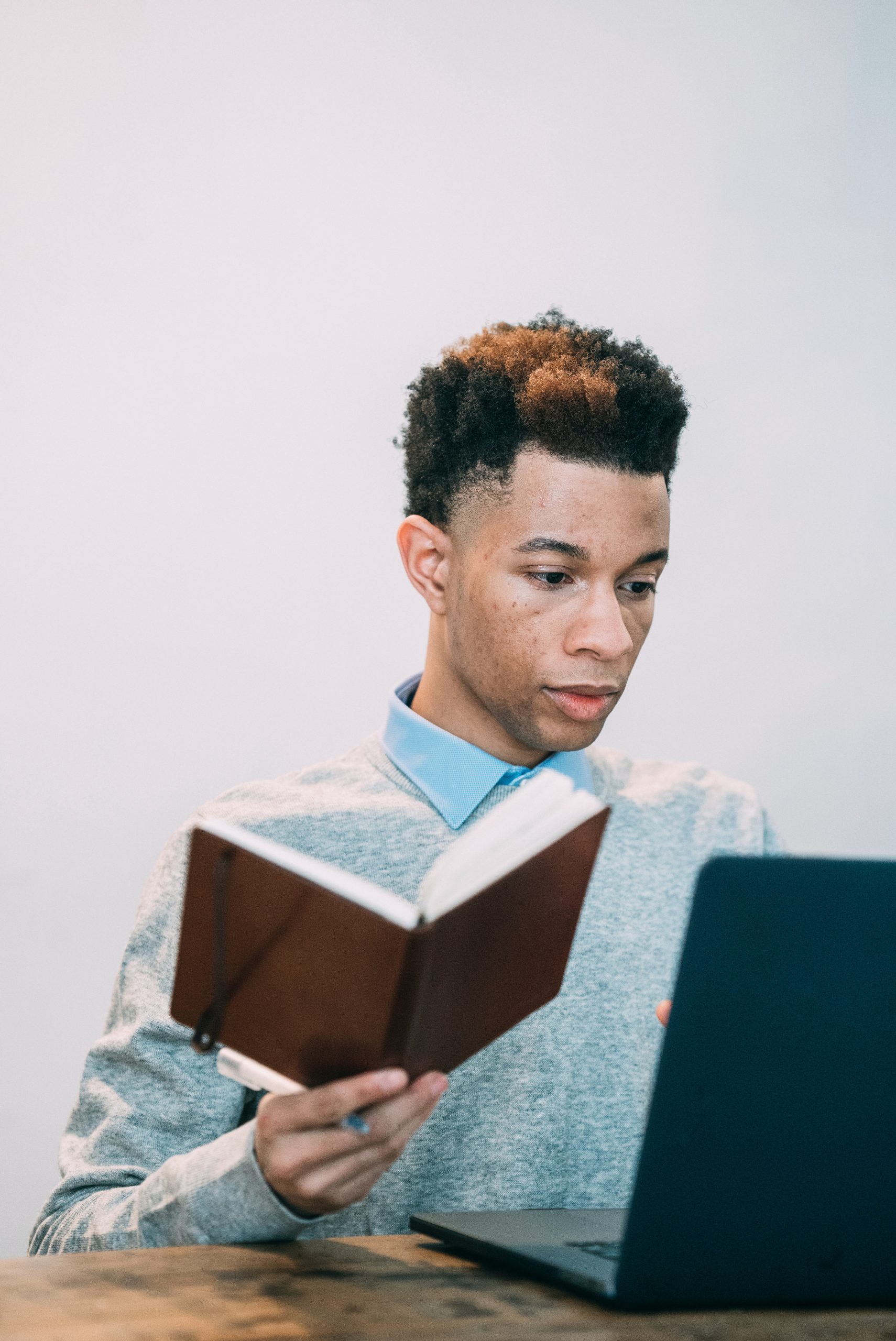 student learning with a book and a laptop